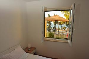 a bedroom with a bed and an open window with an umbrella at Apartments Barbara Sutivan in Sutivan