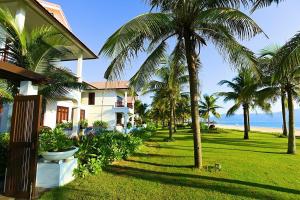 a house with palm trees in front of the ocean at 3BR garden pool villas in beach resort in Da Nang