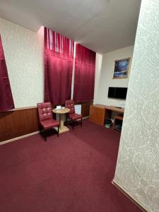 Pokój z 2 krzesłami, stołem i telewizorem w obiekcie Zolotoi Drakon Hotel w mieście Ałma-Ata