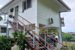 a house with a staircase with a car parked under it at Faré Vaihere in Haapiti