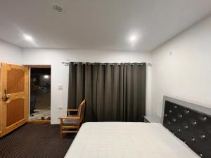 1 dormitorio con cama y cortina gris en Chubar home stay, en Leh