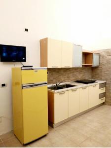 La cuisine est équipée d'un réfrigérateur jaune et d'un évier. dans l'établissement Casal Baratz, à Santa Maria la Palma