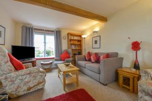 a living room with a couch and a tv at Regatta Cottage in Feock