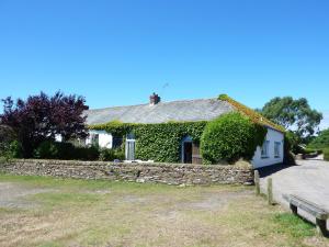 a house with a stone wall and a bench at Regatta Cottage in Feock