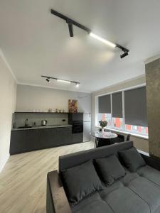 a living room with a gray couch and a kitchen at Больница Управ делами президента , IT Университет, Центр репродукции, Экспо Mega Silkway, Аэропорт in Prigorodnyy