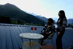 Ein Mann und eine Frau sitzen auf einem Balkon mit Weingläsern in der Unterkunft Hotel Old Manali with Balcony and Mountain Views, Near Manali Mall Road in Manali