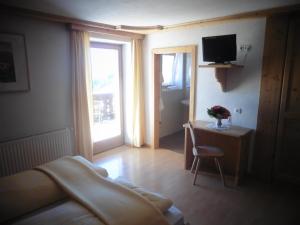 a bedroom with a bed and a television and a chair at Chalet Frapes in San Martino in Badia
