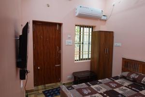 a bedroom with a bed and a television and a window at Wisma Gokilambal Residency in Tiruvannāmalai