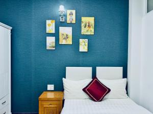a bedroom with a blue wall with a bed and pictures at Dalat ECO Hotel 2 in Da Lat