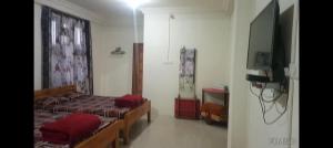 a bedroom with two beds and a flat screen tv at Breeze Hills Inn in Cherrapunji