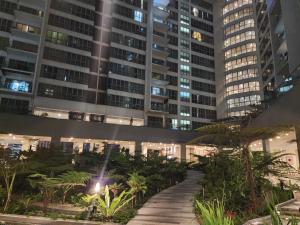 une passerelle devant un grand bâtiment la nuit dans l'établissement Regalia Serviced Suites KLCC Infinitypool, à Kuala Lumpur