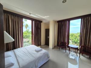 Una habitación de hotel con una cama y grandes ventanales. en Goa Ganesha, en Nusa Dua