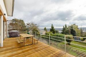 una terrazza in legno con tavolo e sedie sul balcone. di Grande villa 20 min de Paris centre a Garches