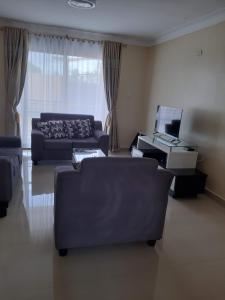 ein Wohnzimmer mit 2 Sofas und einem TV in der Unterkunft VILLA FIORI APARTMENTS in Arua
