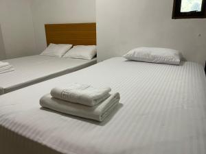 2 camas en una habitación con sábanas blancas y toallas en Palace Hostel พาเลส โฮสเทล en Amphoe Phra Khanong