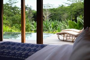 a bedroom with a bed and a view of a pool at Villa Sama Sama 2BR Jungle View in Uluwatu