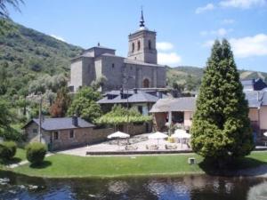 un grande edificio con una chiesa sullo sfondo di The Way Hotel Molinaseca a Molinaseca