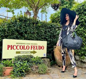 Una donna è in piedi davanti a un cartello di Piccolo Feudo Green Resort a Viterbo