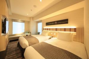 a hotel room with two beds and a television at Hotel Sunroute Ginza in Tokyo