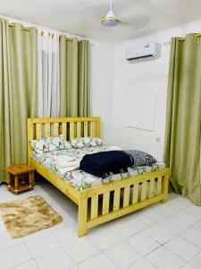 Cama de madera en habitación con cortinas verdes en Mikocheni Full House - 1 Bedroom en Dar es Salaam