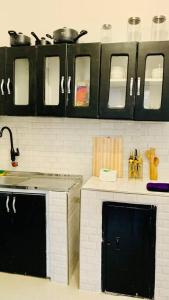 eine Küche mit schwarzen Schränken und einer Arbeitsplatte in der Unterkunft Mikocheni Full House - 1 Bedroom in Daressalam