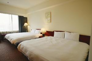 2 łóżka w pokoju hotelowym z białą pościelą w obiekcie T Hotel w mieście Taizhong