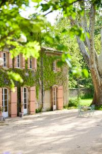 un bâtiment avec des portes roses et un banc devant lui dans l'établissement Chambre d'hôtes insolite lit rond B&B proche Avignon Orange - Château de Sienne Piscine Rivière, à Chusclan