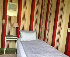 Bett in einem Zimmer mit gestreifter Wand in der Unterkunft Land und Leute - Landleben Fewo 1 in Fritzlar