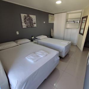 two beds in a hotel room with white sheets at Apartamento Docelar Garagem Feirinha e Hospitais in São Paulo