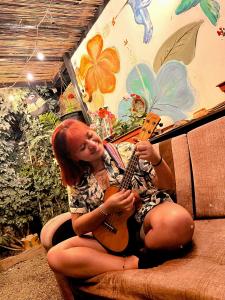 Una donna seduta su un divano che suona la chitarra di Samanai Wasi Hostel a Lima