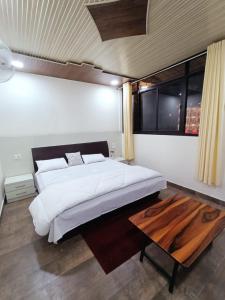 a bedroom with a large bed and a wooden table at Singhdwar Homestay in Joshīmath