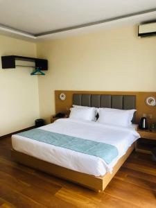 a bedroom with a large white bed with wooden floors at Fashion International Hotel in Dar es Salaam