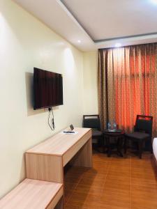 Habitación con escritorio y TV en la pared. en Fashion International Hotel en Dar es Salaam