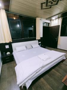 duże białe łóżko w pokoju z oknami w obiekcie Singhdwar Homestay w mieście Jyotirmath