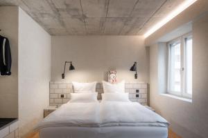 een slaapkamer met een bed met witte lakens en kussens bij B5 Boutique Hotel - NEW OPENING in Lugano