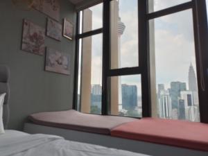 posto a sedere vicino alla finestra in una camera da letto con vista sulla città di Ceylonz Suite By ANA MALAYSIA a Kuala Lumpur