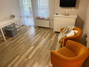 sala de estar con suelo de madera, silla y TV en Brzozowy zakątek, en Królewo