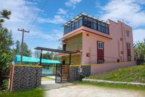 una casa rosa con una puerta delante en JK Resort, en Yercaud