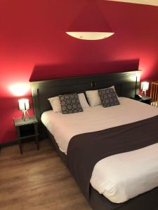 a bedroom with a large bed with a red wall at Logis Hôtel Le Moulin de la Coudre in Venoy