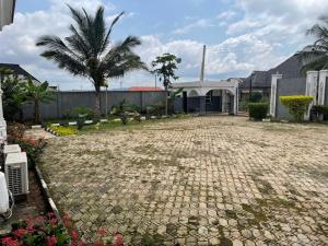 une allée en briques avec un palmier et un bâtiment dans l'établissement Royal Diadem Villa, à Ile-Ife