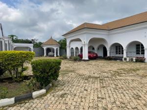 Ein weißes Gebäude mit einem roten Auto in einer Einfahrt. in der Unterkunft Royal Diadem Villa in Ile-Ife