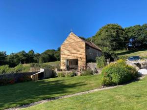 a small wooden house on a hill with a yard at The Barn at Tanlake in Buckland St Mary