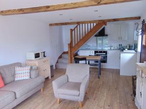 a living room with a couch and a table and a kitchen at The Barn at Tanlake in Buckland St Mary