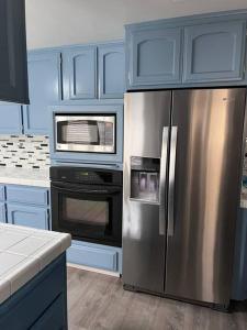 a kitchen with blue cabinets and a stainless steel refrigerator at Entire 3 BR & 2 BA house for business and family in Modesto