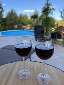 Dois copos de vinho tinto numa mesa de madeira. em Dom niedaleko jezior i lasu z basenem i jacuzzi em Sząbruk