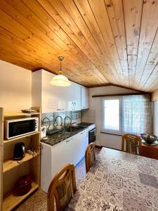 uma cozinha com tecto em madeira e uma mesa com cadeiras em Holiday House Lärchenheim em Saas-Balen