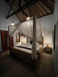 Schlafzimmer mit einem Bett mit Moskitonetz in der Unterkunft Ariwigangga Garden Guest House in Krambitan