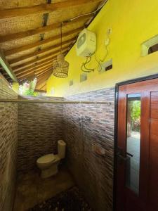 a bathroom with a toilet in a brick wall at Ariwigangga Garden Guest House in Krambitan