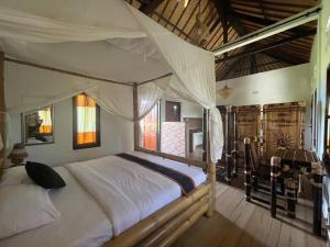 a bedroom with a large bed with a canopy at Ariwigangga Garden Guest House in Krambitan