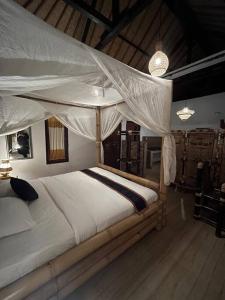 ein Schlafzimmer mit einem großen Bett mit Baldachin in der Unterkunft Ariwigangga Garden Guest House in Krambitan